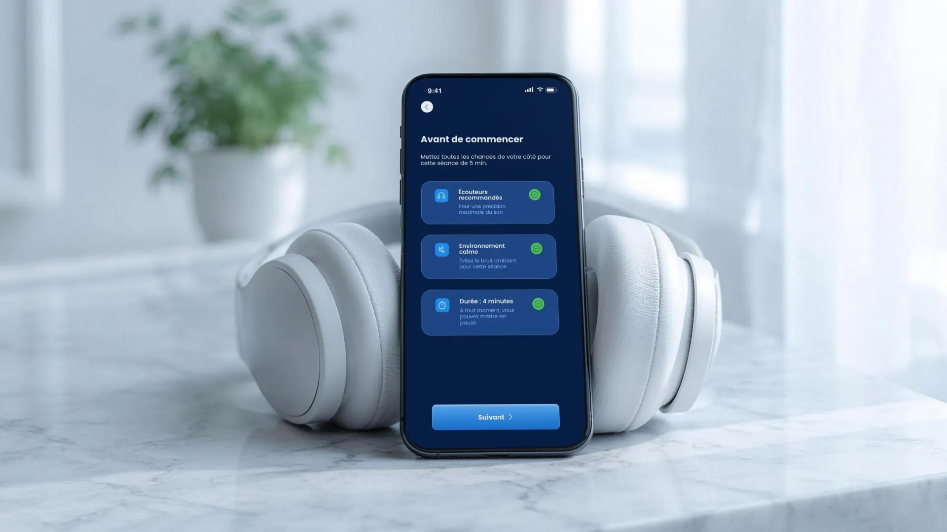 Un iPhone posé entre les écouteurs d’un casque, sur une tablette de marbre. À l’écran, AudiCheck&nbsp;: «&nbsp;Avant de commencer&nbsp;» et les trois consignes de la séance.