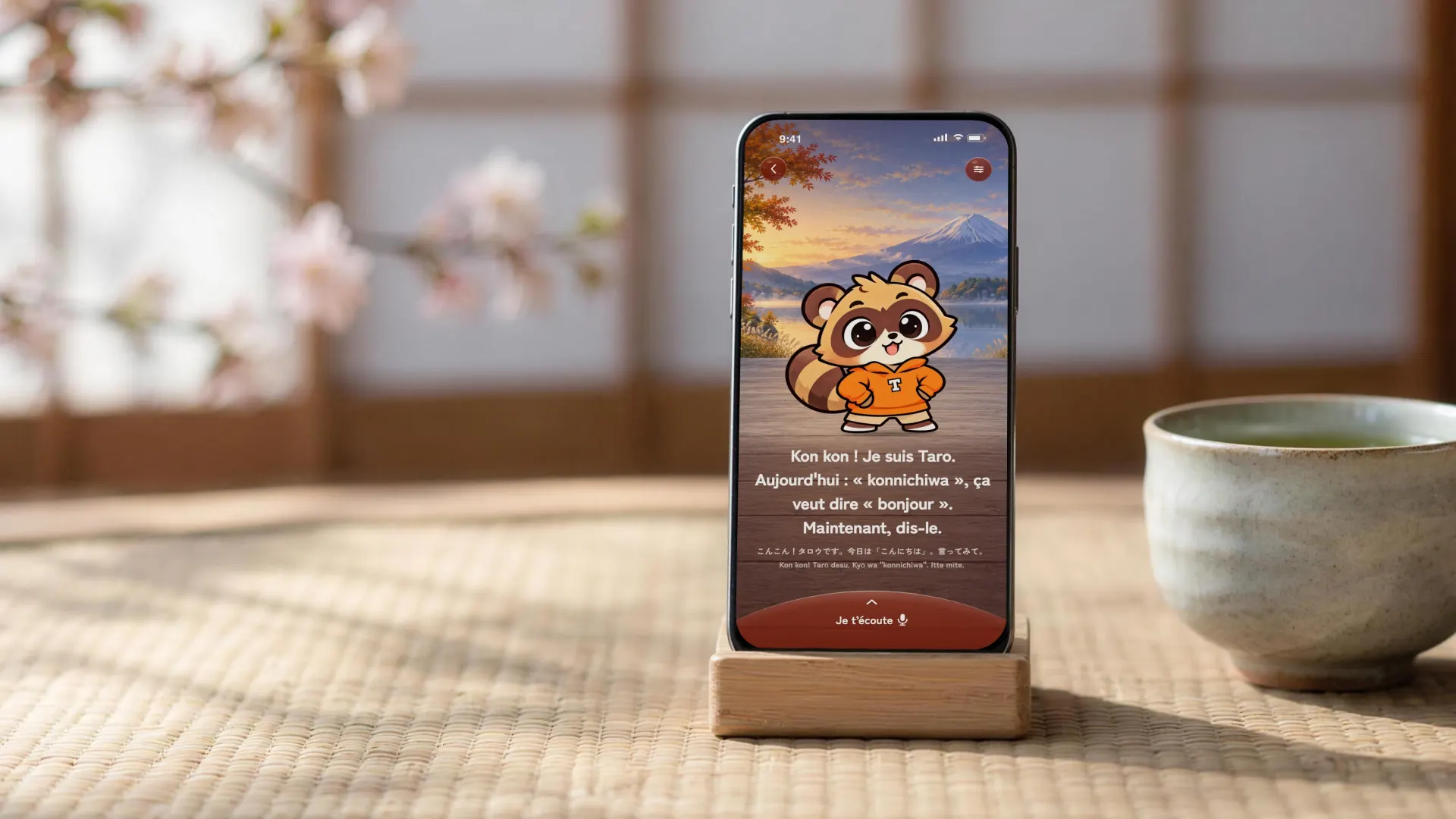 Un iPhone dans un support de bois, sur un tatami, devant des fleurs de cerisier. À l’écran, Talkana&nbsp;: Taro enseigne «&nbsp;konnichiwa&nbsp;», qui veut dire «&nbsp;bonjour&nbsp;».